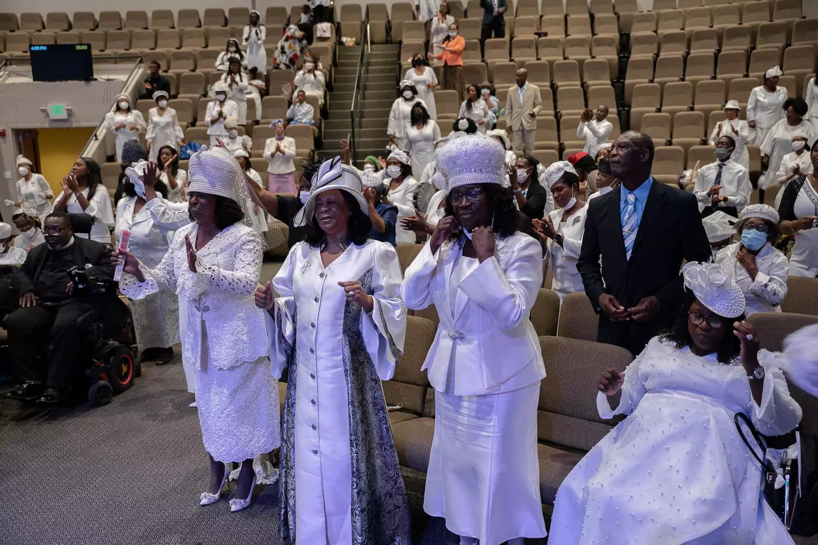 A group of apostolic individuals standing in a church wearing white hats.